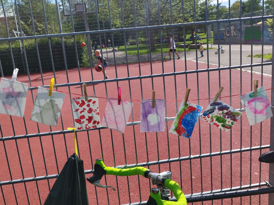 Kunstwerke von Kindern hängen vor dem Basketballplatz